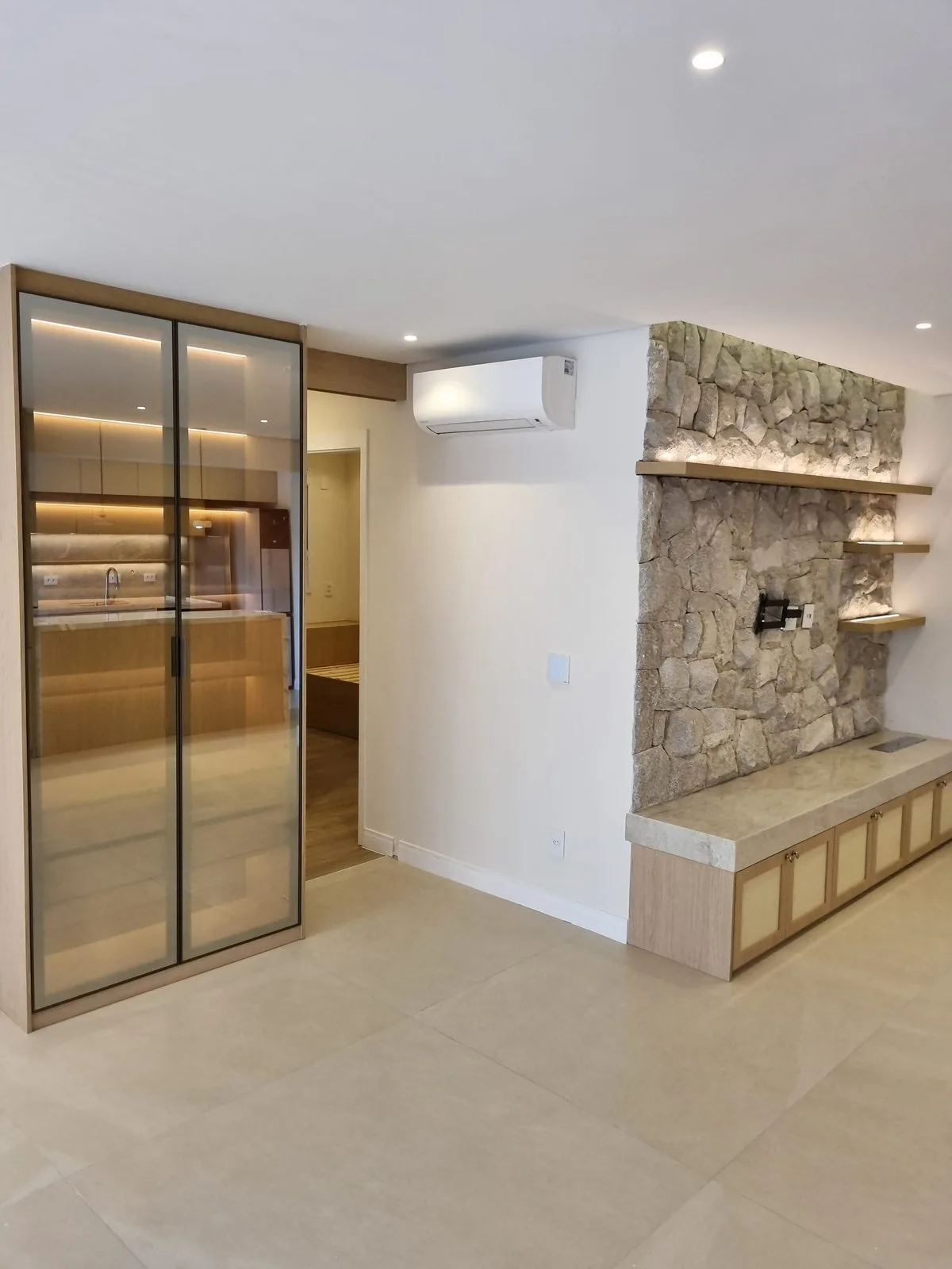 Apartamento Morumbi: sala com parede de pedra e marcenaria